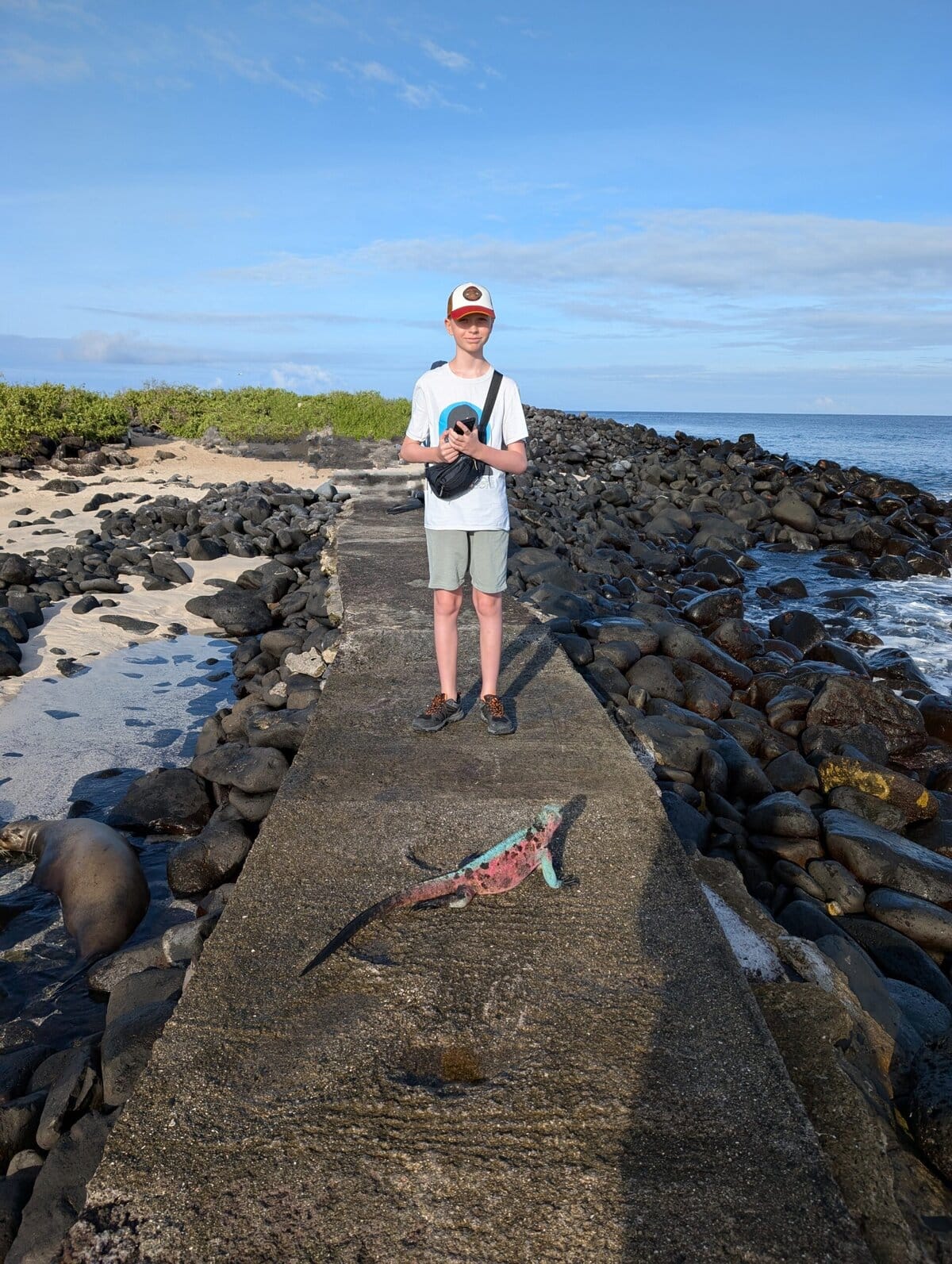Boy stood behind an iguana on the Galapagos Islands