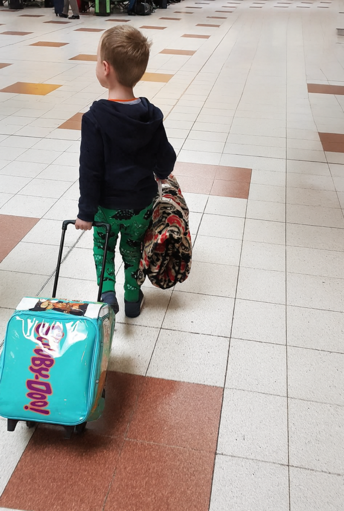Boy in airport pulling his suitcase behind him