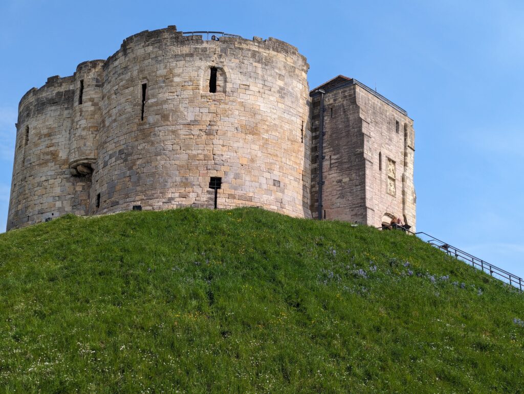 Historic York castle on a grassy hill with clear blue sky, perfect for budget-friendly travel guides.