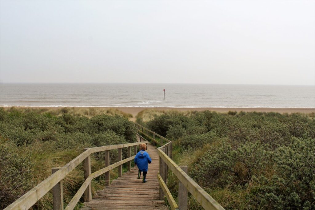 Child walking down a wooden walkway to Anderby Beach, Lincolnshire