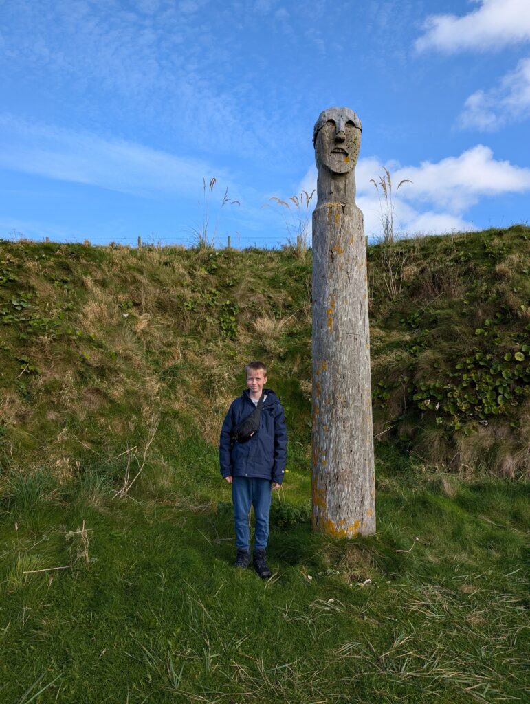 Boy standing next to the Viking Totem Pole on Orkney