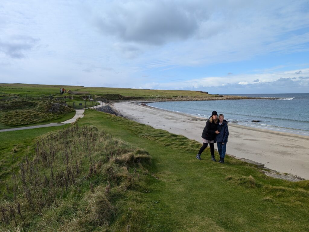 Two people stood beside a beautiful beach in Orkney Scotland