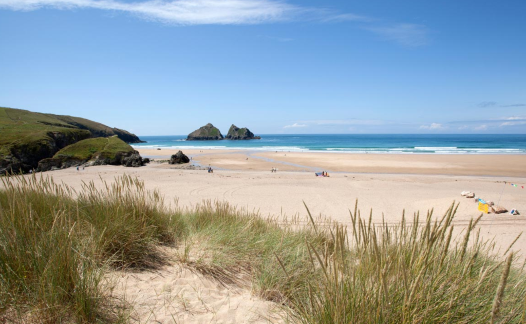 The beach with grass and blue sky at Holywell Bay Park Dean Resorts
