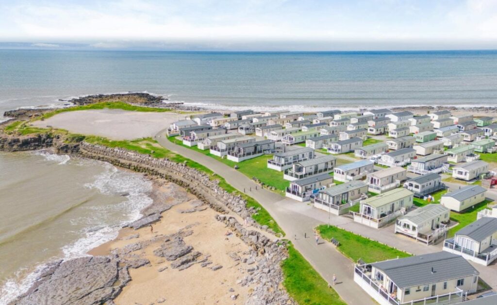 View of holiday lodges by a beach and the sea at Trecco Bay Park Dean